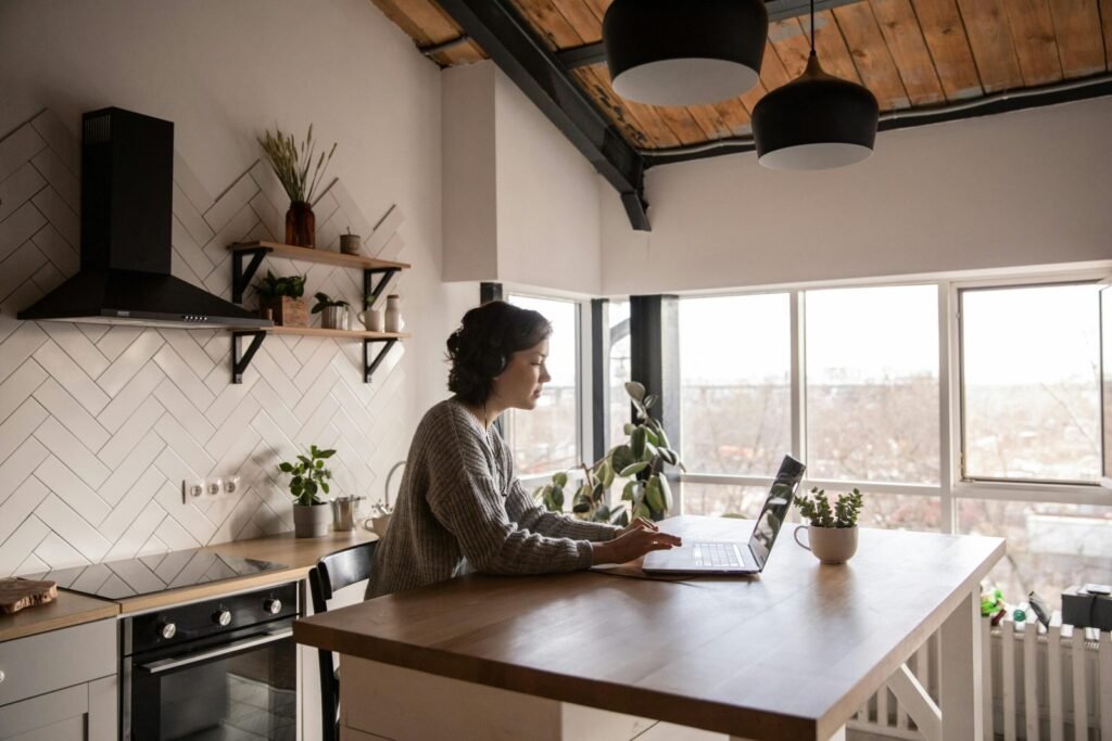 Woman on laptop in a well-lit kitchen space