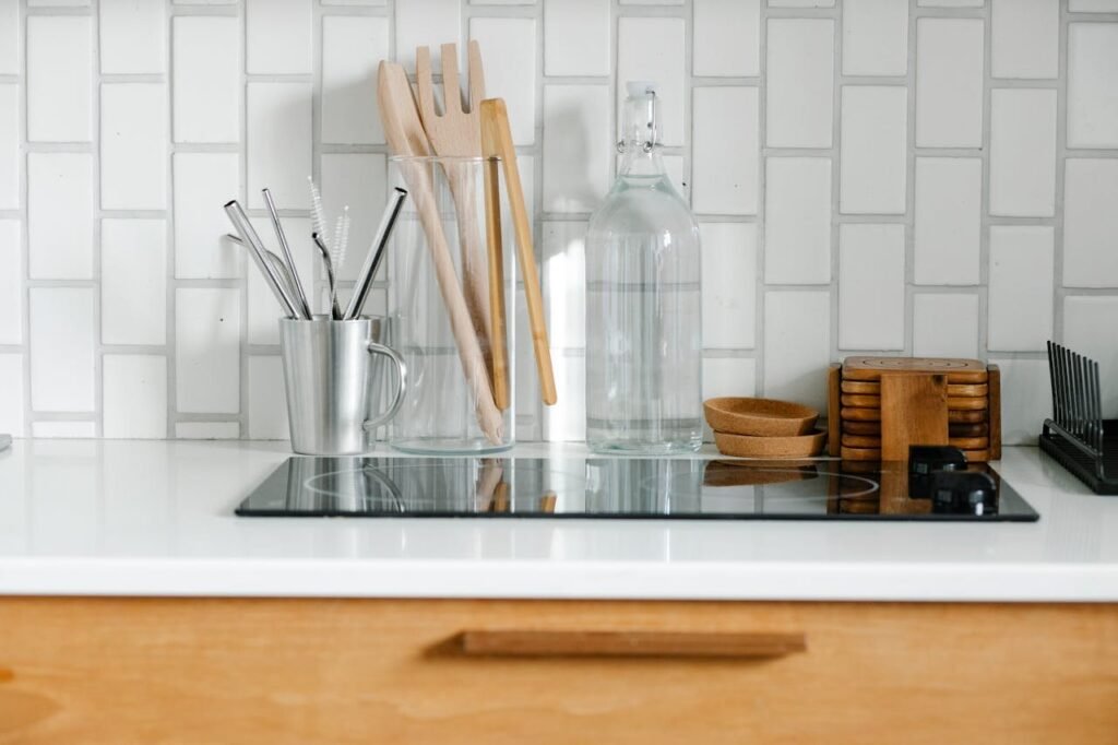 Kitchen counter with induction stove, metal, glass, and wooden utensils