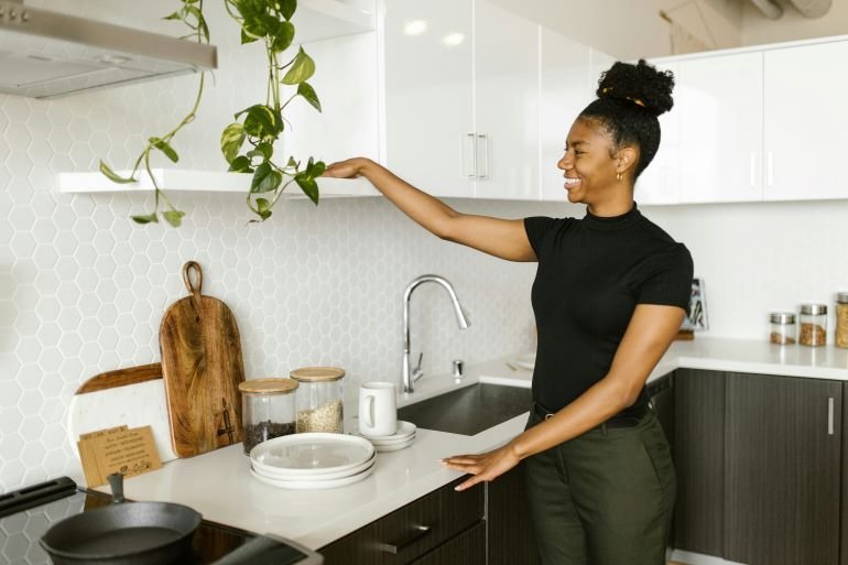 Woman organizing kitchen counter with efficient storage solutions.
